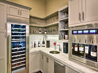 This bar combines soft grey shaker style doors and neutral-colored materials to provide a sense of calm and comfort. The uniquely hammered nickel sink, faucet, and door add interest to the space.