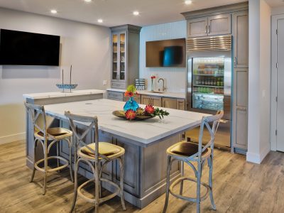 Bar chairs set next to the warm gray shaker style door cabinets. A quartz countertop island invites guests to linger, socialize, and cheer for their team. Entertaining is easy with two TV’s, glass paneled refrigeration, ice machine, dishwasher and sink. Now it is time to shake and stir drinks, serve food and cheer for your favorite team.